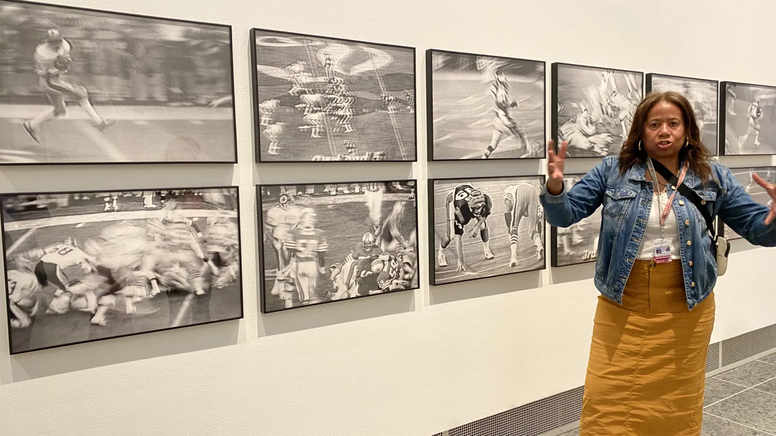 A member of the Association for African Studies Programs in front of eight black and white pictures.